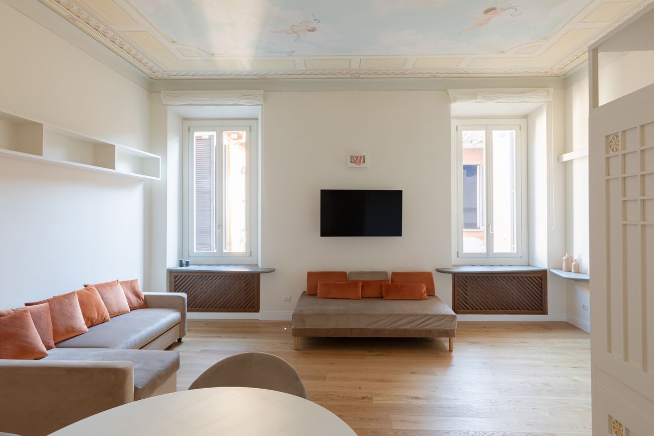 Soggiorno con due finestre, soffitto dipinto e parquet in rovere