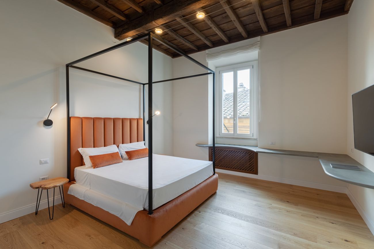 Camera con letto a baldacchino, testiera in velluto e soffitto a travi